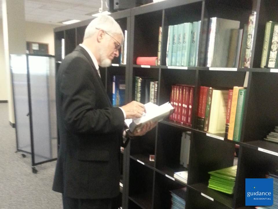 man looking at book on bookshelf