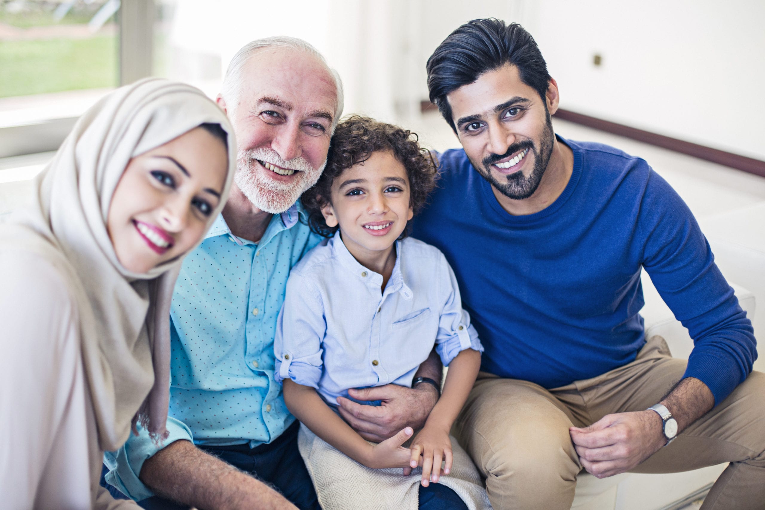 Muslim family portrait, kid, parents and grandfather all looking at the camera.